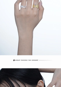 Close-up of textured silver open ring and gold ring with purple stone on model fingers