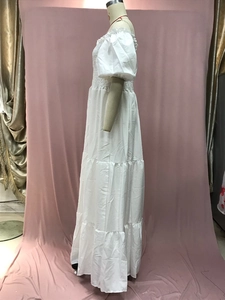 Detail of white off-shoulder maxi dress featuring elastic smocked bodice and tiered skirt