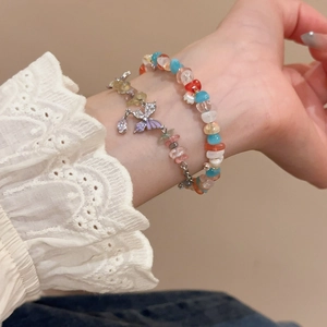 Close-up of beaded bracelet and silver chain with purple butterfly charm and gemstones