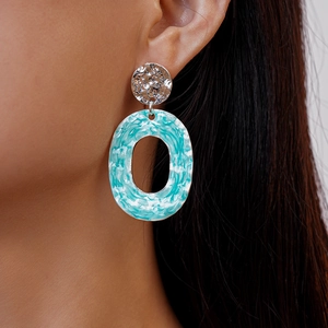 Detail shot of hammered silver earrings with blue marble patterned oval pendants on ear