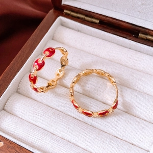Close-up of 18k gold plated oval red enamel rings in a premium wood jewelry box