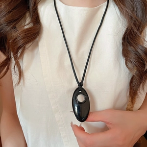 Close-up of minimalist black oval geometric pendant on thin leather cord necklace