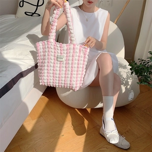 Detail of pink plaid popcorn fabric texture and brand label on a soft tote bag