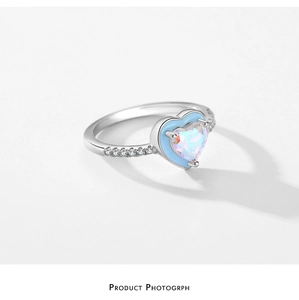 Macro view of S925 silver ring with opal-textured heart gem and blue enamel edge