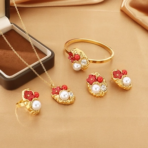 Detailed set of gold jewelry with red flower charms and white pearls on gold silk