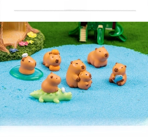Detailed view of capybara figurines with orange and crocodile in a miniature garden