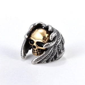Bague punk gothique avec ailes en plumes argentées et crâne doré sur fond blanc pur