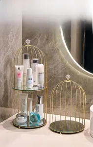 Macro shot of two-tier golden birdcage cosmetic organizer with glass shelves on a marble counter