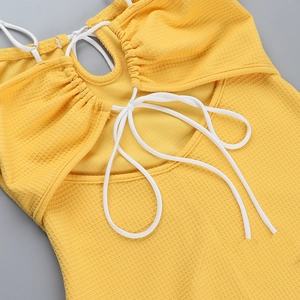 Détail d'une robe jaune avec texture gaufrée et design à lacets dans le dos