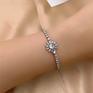 Detailed view of sparkling silver sunflower zircon bracelet worn on a champagne silk background