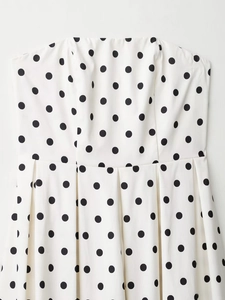Gros plan du motif à pois noirs et blancs et texture plissée sur la robe d'été
