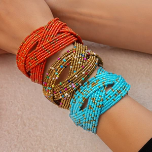 Close-up of bohemian multi-layer seed bead bracelets in orange, gold and blue on wrist