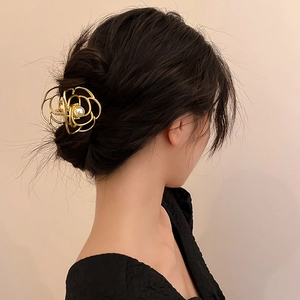 Detailed view of a gold rose hair claw with a pearl accent used in a high bun hairstyle