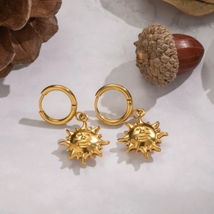 Retro 18K gold plated stainless steel sun face drop earrings on a white stone background