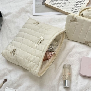 Detailed macro view of quilted cream makeup bag featuring cute rabbit embroidery and zip