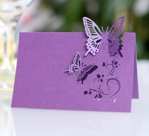 Macro detail of purple laser-cut wedding place card with intricate butterfly and floral patterns
