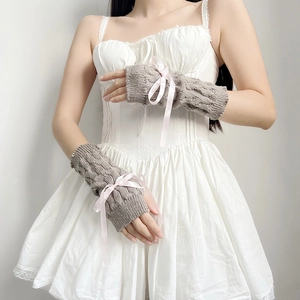 Detail of grey knitted arm warmers with pink ribbon bows on a model against white wall