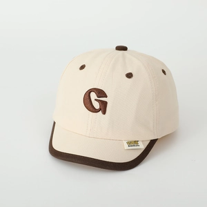 Detail of 3D embroidered letter G on a beige and brown kids baseball cap fabric