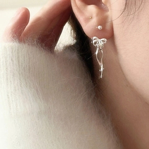 Elegant silver ribbon bow earrings for women shown worn on a model in a close-up shot
