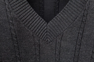 Detail eines V-Ausschnitt Strickpullovers mit klassischem dunkelgrauem Zopfstrickmuster