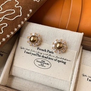 Detailed shot of champagne pearl stud earrings with white zircon halo in a wooden box