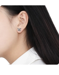 Close-up of minimalist black butterfly S925 silver stud earring on female ear