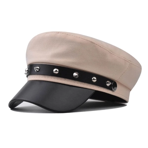 Dettaglio del cappello beige con visiera in ecopelle nera e cinturino con borchie metalliche