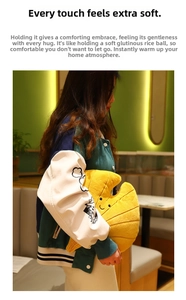 Detail of soft croissant-shaped plush pillow with cute smile face held by model