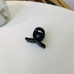 Detail showing the glossy black spiral claw clip with a strong metal spring mechanism