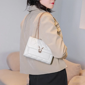 Detail of white quilted crossbody bag with gold deer-head clasp on female model