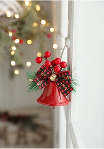 Christmas bell ornament with plaid bow and red berries hanging on white cabinet handle