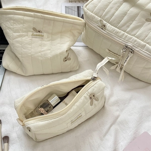 Detail of three-piece cream quilted storage bags with cute rabbit embroidery and zip closure