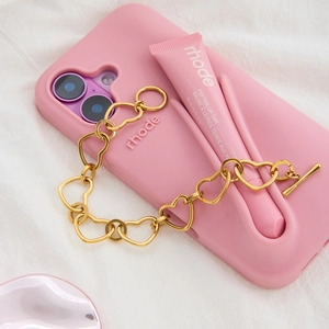 Pink silicone phone case with gloss holder and gold heart chain accessory on fabric