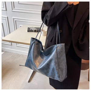 On-shoulder view of a large navy gray tote bag in oil wax texture with a minimalist design