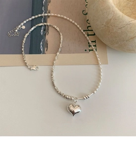 Detail of pearl and irregular silver bead necklace featuring a 3D heart-shaped pendant