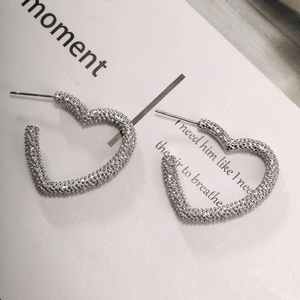 Detail of silver heart-shaped stud earrings with textured finish on a white background