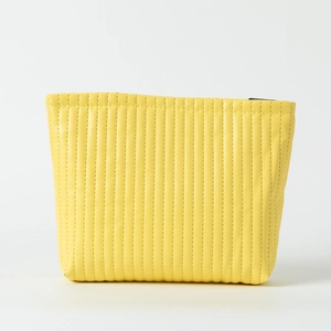 Close-up of bright yellow quilted makeup bag with vertical stitching and zipper
