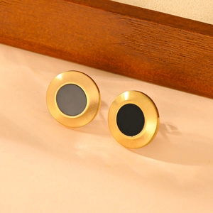 Detailed macro view of matte gold titanium steel earrings with black resin inlay work