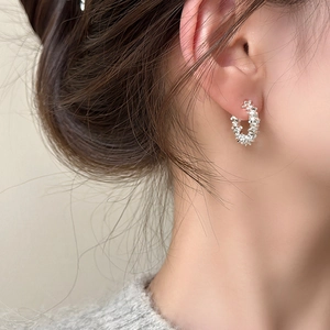 Detailaufnahme des unregelmäßigen silbernen C-Ohrrings am Ohr mit glitzernder Textur