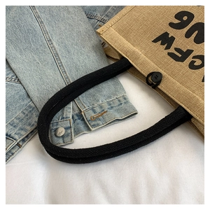 Detailed texture of beige linen tote bag with black rope handles and printed logo