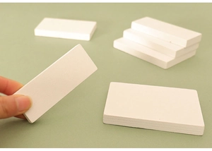 Detailed view of hand holding small white rectangular wooden blocks for DIY dollhouse