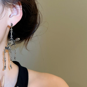 Detailed view of silver skull tassel earrings worn by model with high-end dark aesthetics