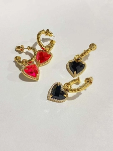 Dettaglio di orecchini a cuore rossi e neri placcati in oro con zirconi brillanti