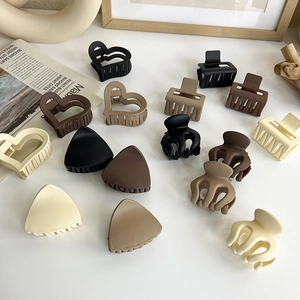 Variety of matte resin hair claws in earth tones and geometric shapes on a white surface