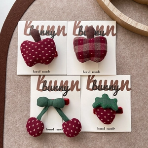 Detailed view of handmade fruit fabric hair clips including apple and cherry patterns