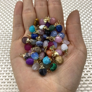Assorted 8x14mm faceted natural stone oval pendants with metal loops held in hand