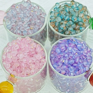 Macro view of assorted frosted glass beads with gold specks in glass cups for DIY crafts