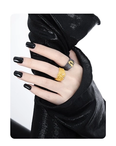 Close-up of textured gold and black wide band rings with a diamond on hand