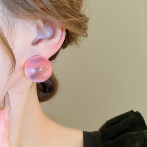 Gros plan d'une boucle d'oreille en résine rose translucide portée avec texture gelée