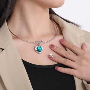 Polished stainless steel choker featuring a large emerald green heart-shaped glass pendant